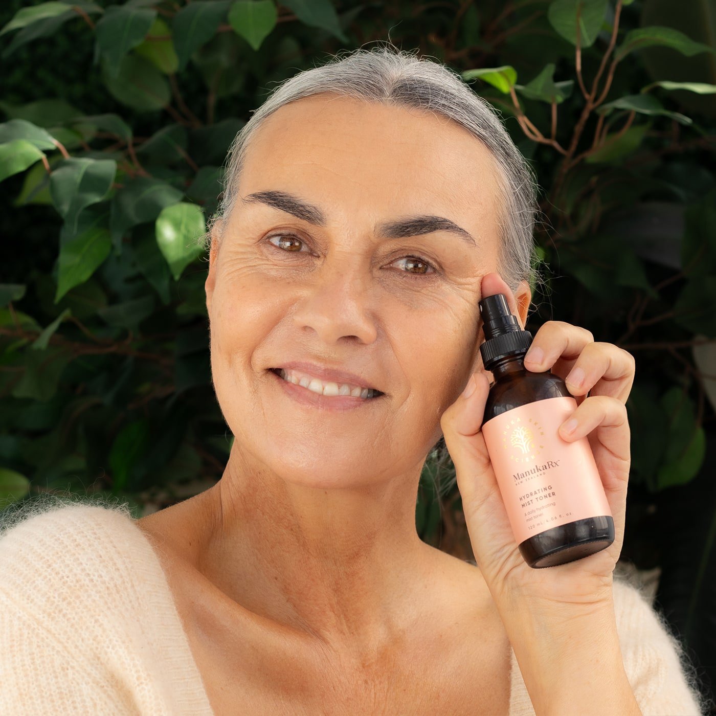 Woman holding bottle of ManukaRx Hydrating Mist Toner