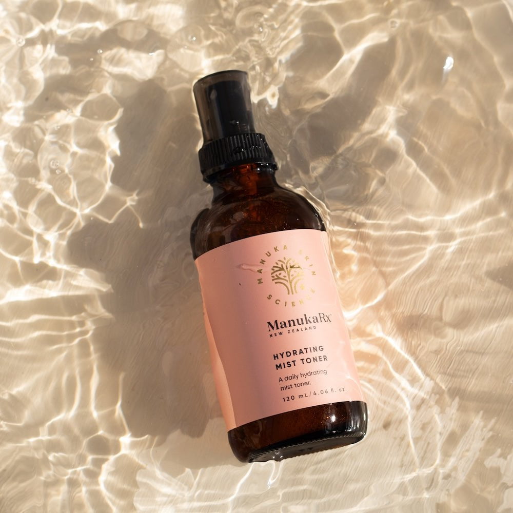 Bottle of ManukaRx Hydrating Mist Toner with water background