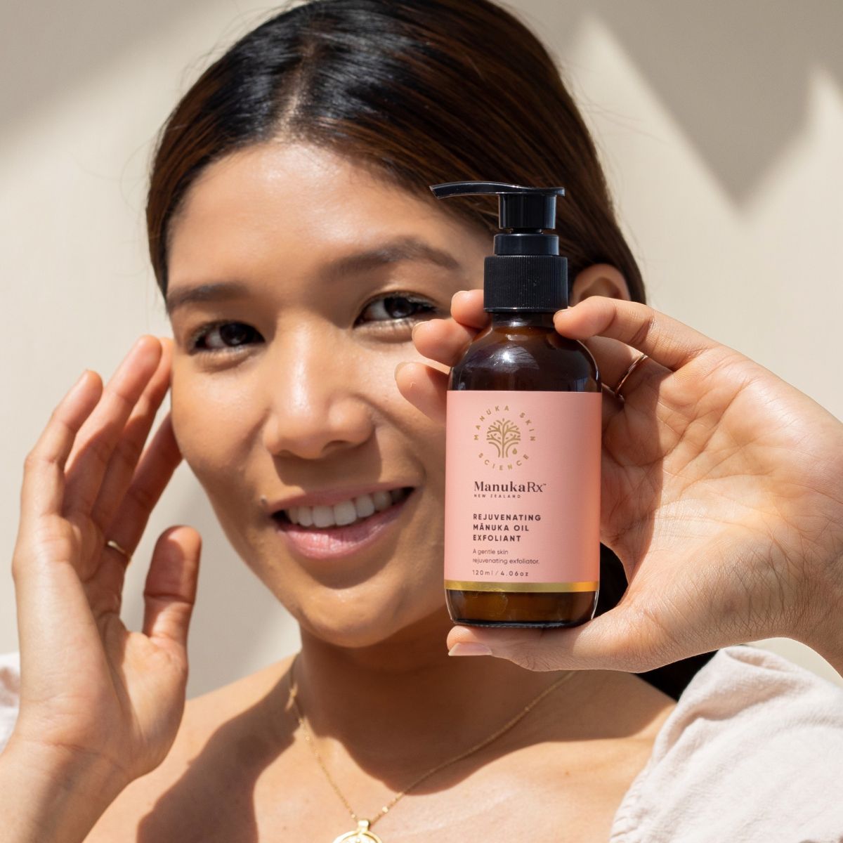 Woman holding bottle of Rejuvenating Mānuka Oil Exfoliant
