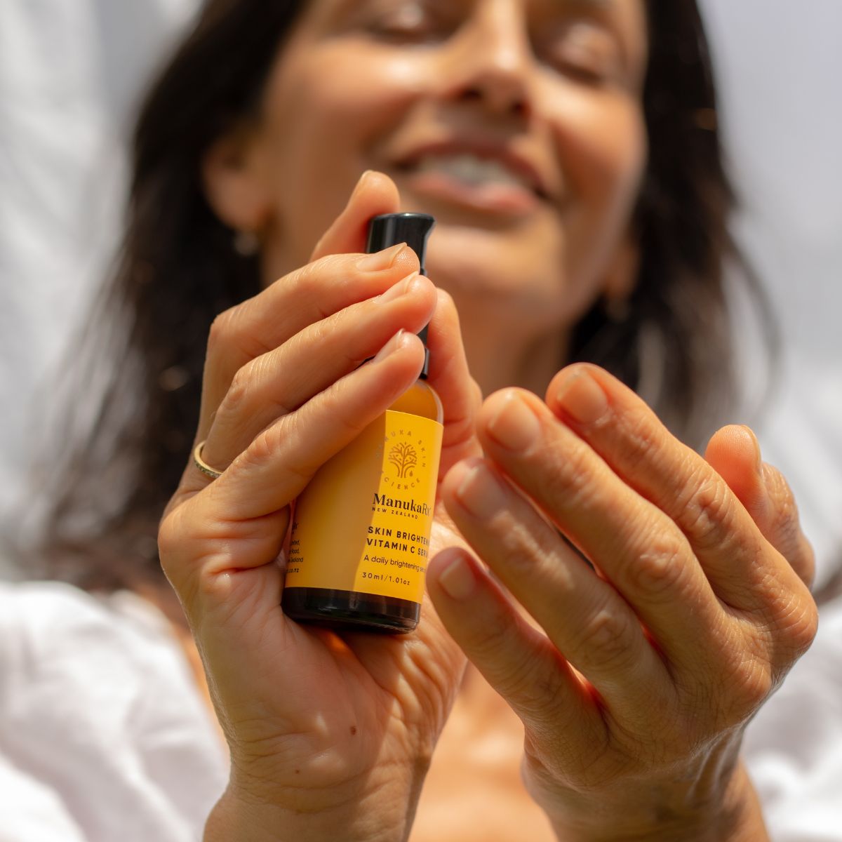 Woman pumping ManukaRx Skin Brightening Vitamin C Serum on to her fingertips