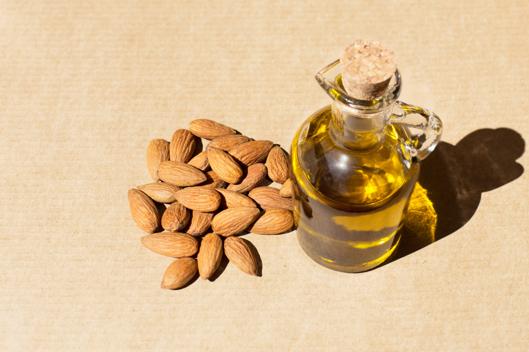 5 Sweet Almond Oil Benefits That Lead to Better Skin - A vile of glowing sweet almond oil on a wooden table.