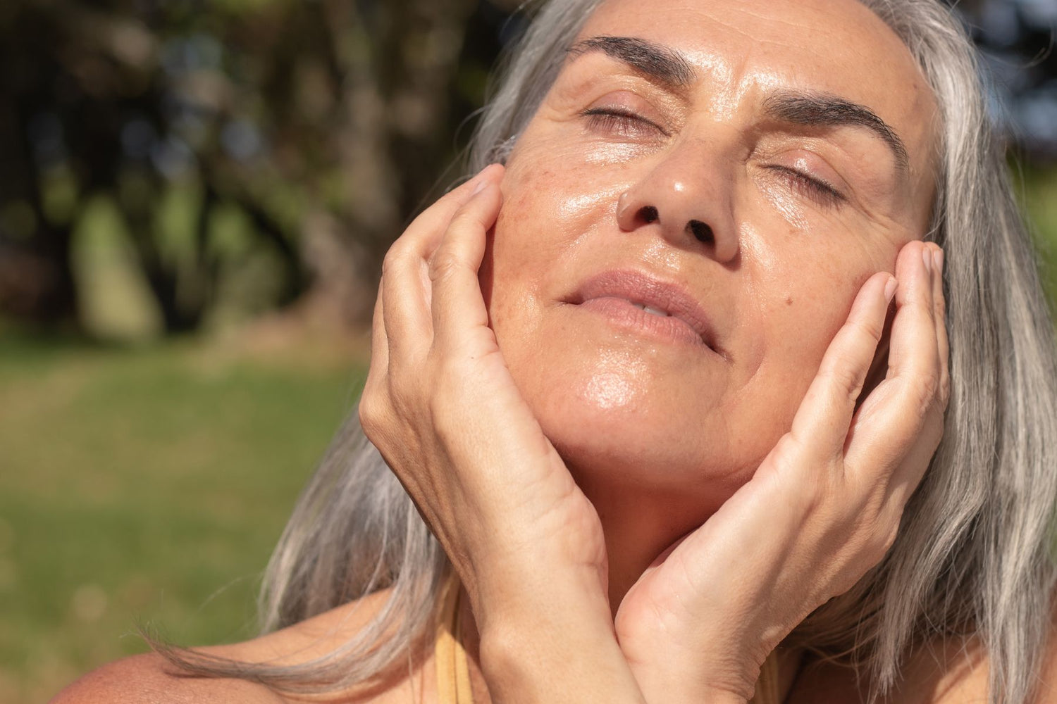 Radiant woman with glowing, healthy skin embracing the warmth of the sun.