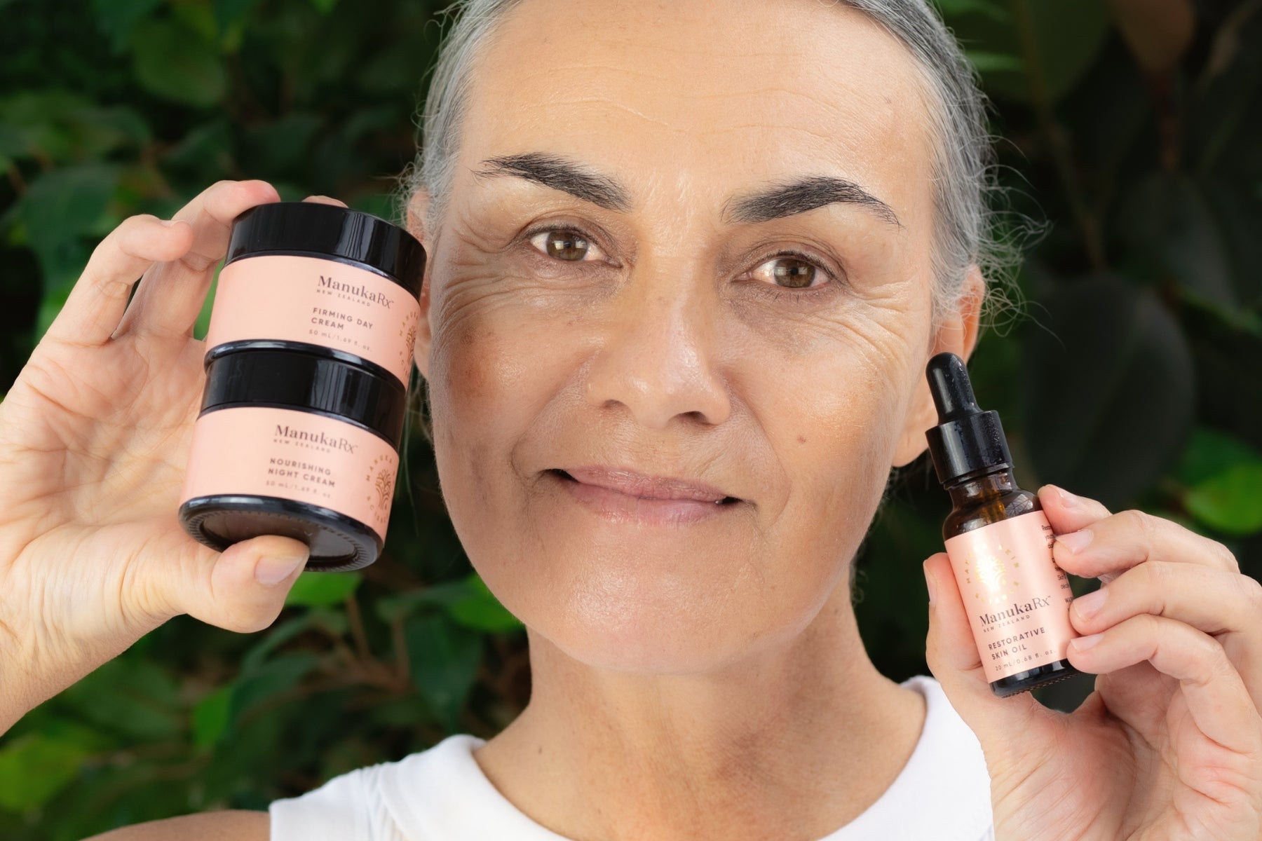 3 Incredible Skincare Products For Mature Skin blog image featuring a mature woman holding ManukaRx Day Cream and Night Cream for anti-aging benefits.