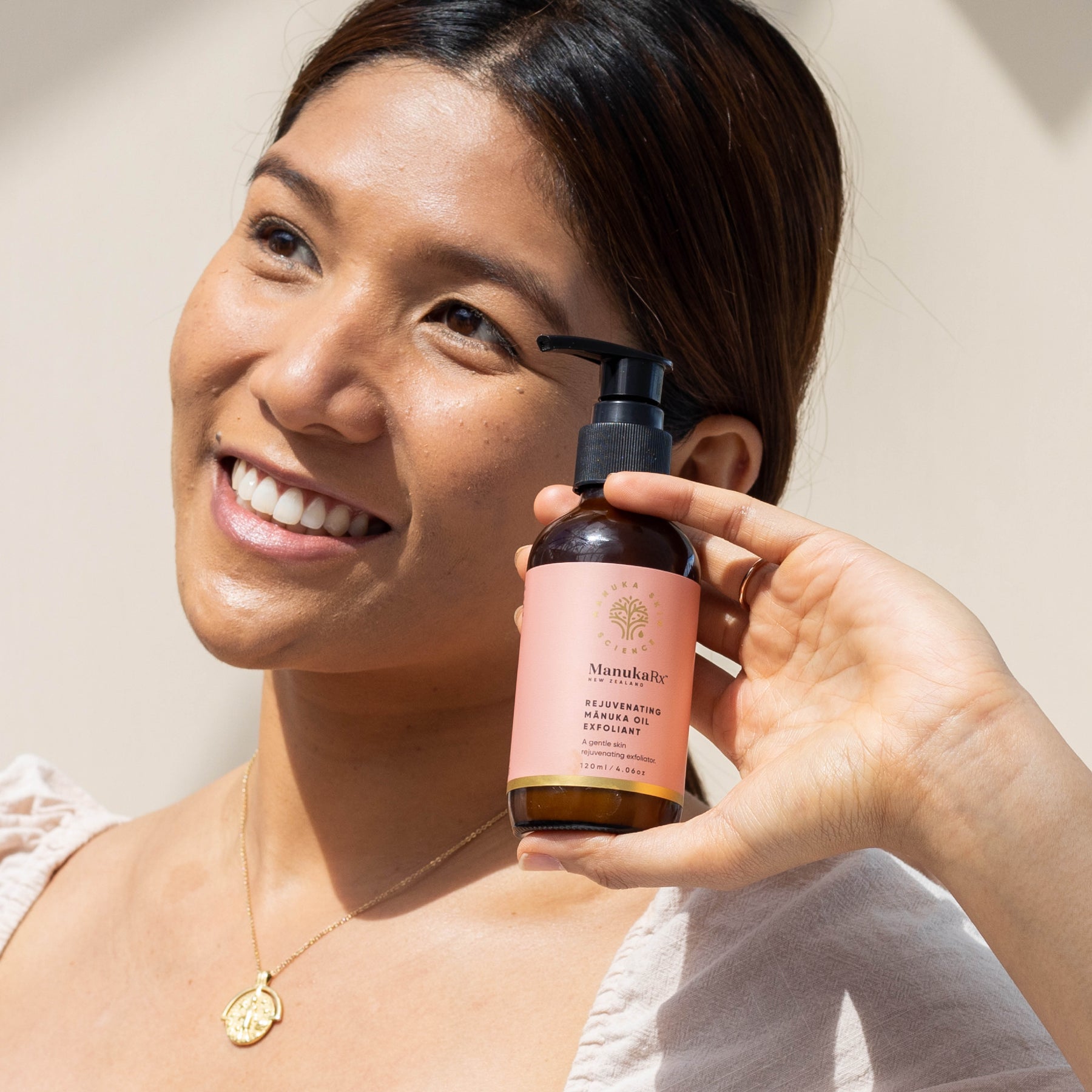 Woman holding bottle of Rejuvenating Mānuka Oil Exfoliant