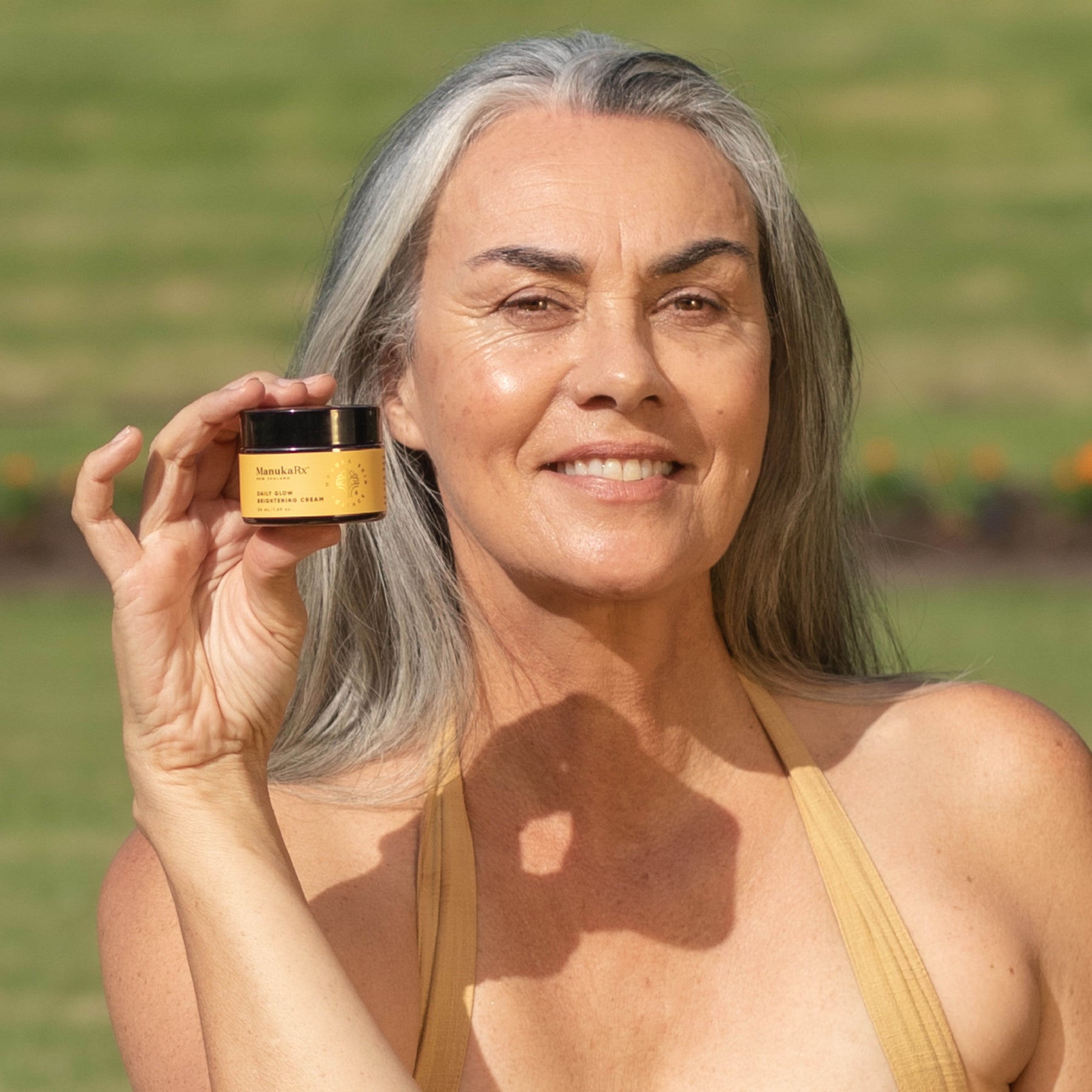 Woman holding jar of ManukaRx Vitamin C Daily Glow Brightening Cream